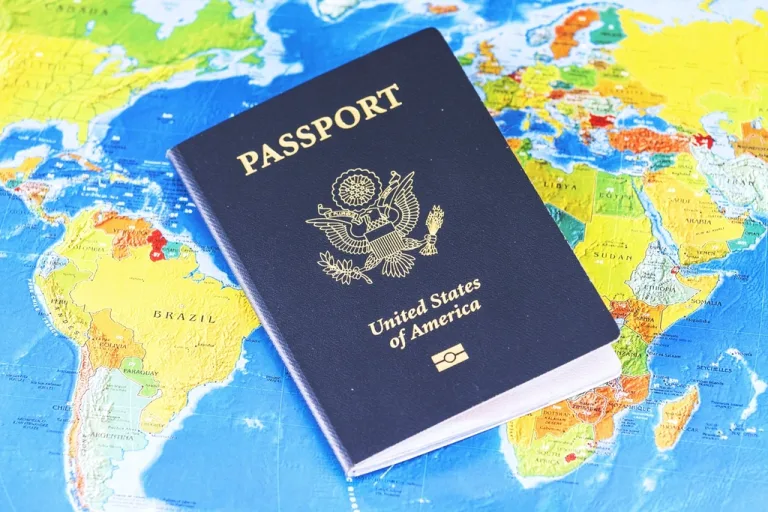 A United States passport resting on a colorful world map