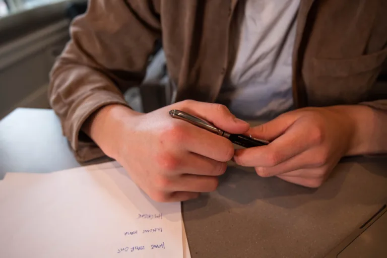 Hands holding a pen over handwritten notes at a desk