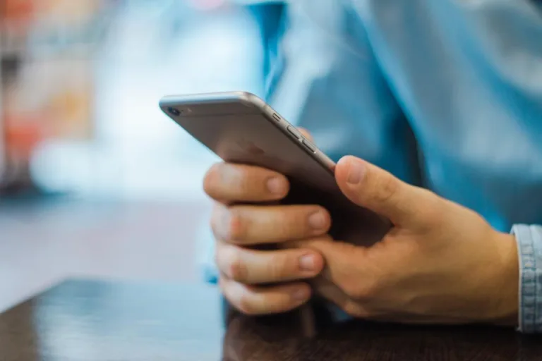 Two hands holding a smartphone at a table