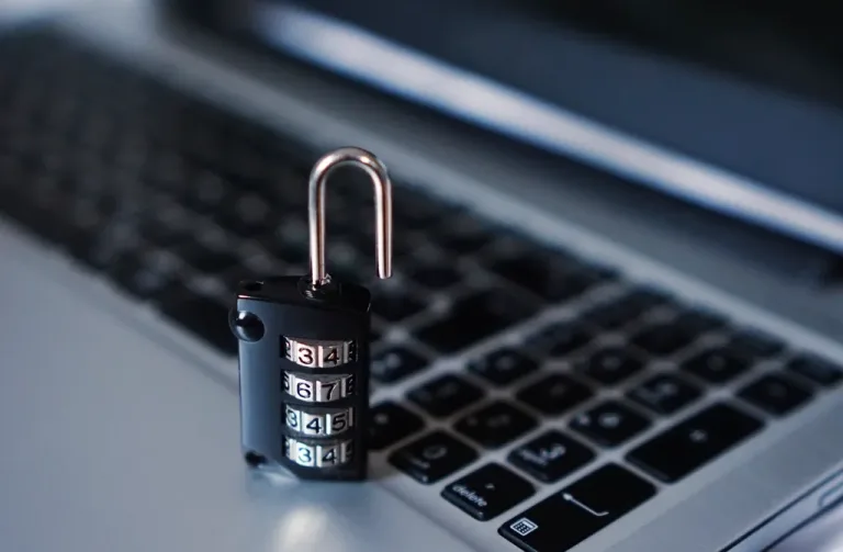 An open combination padlock resting on a laptop keyboard