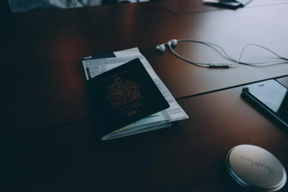 A passport and travel documents resting on a dark wooden desk