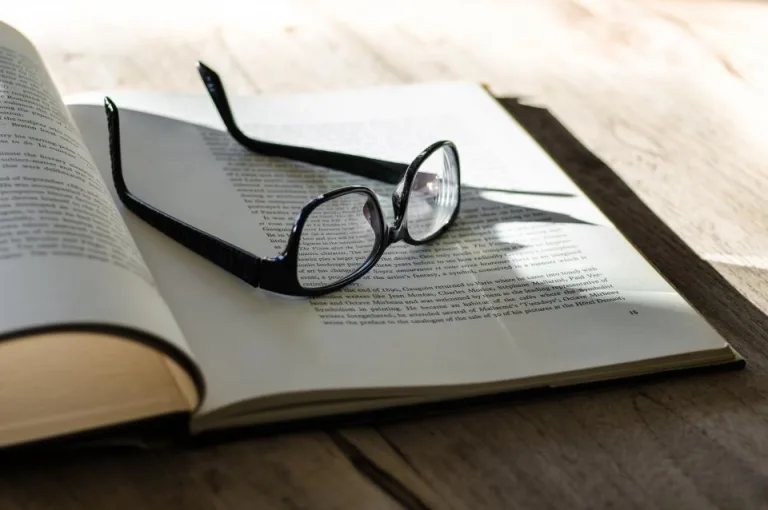A pair of reading glasses resting on an open book
