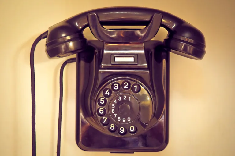 A vintage rotary telephone mounted on a warm-toned wall