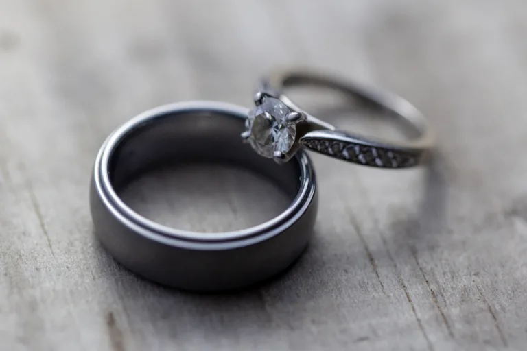 Two wedding rings resting side by side on a gray wooden surface