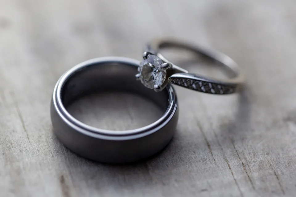 Two wedding rings resting side by side on a gray wooden surface